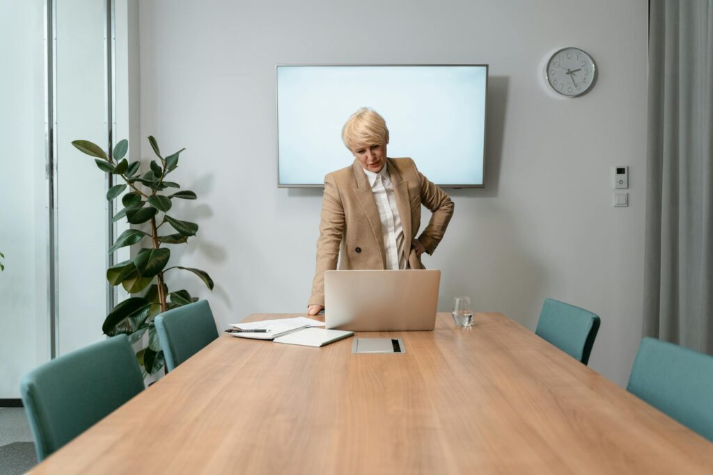 woman in brown suit jacket looking at a computer